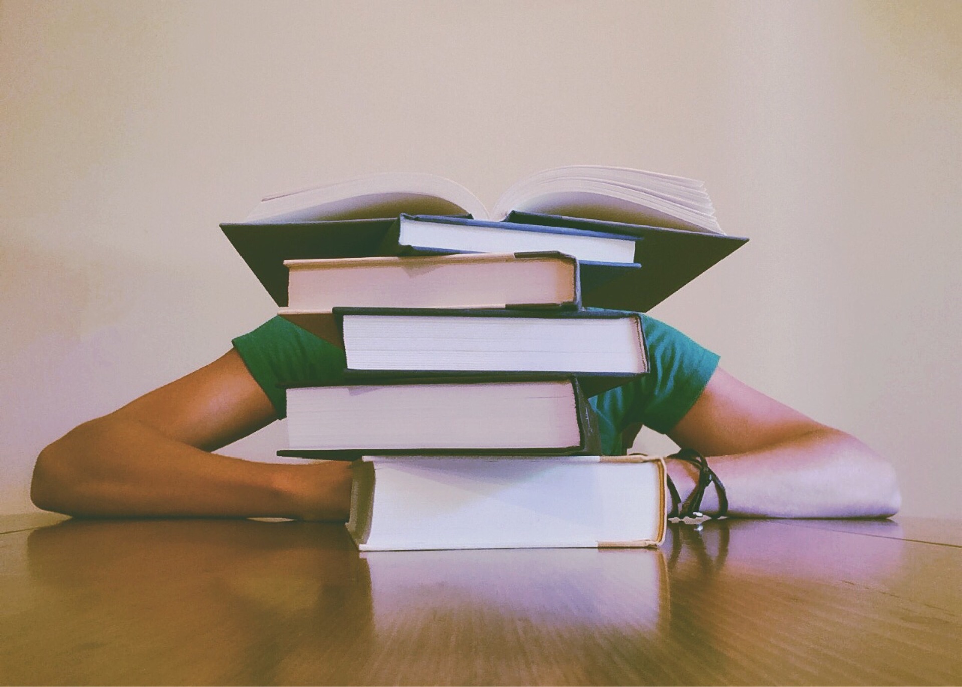 books-927394_1920 Student behind a pile of books