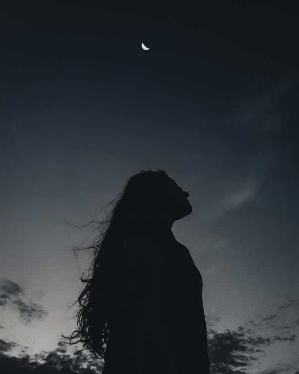 A woman’s silhouette in the dark, looking up contemplatively.