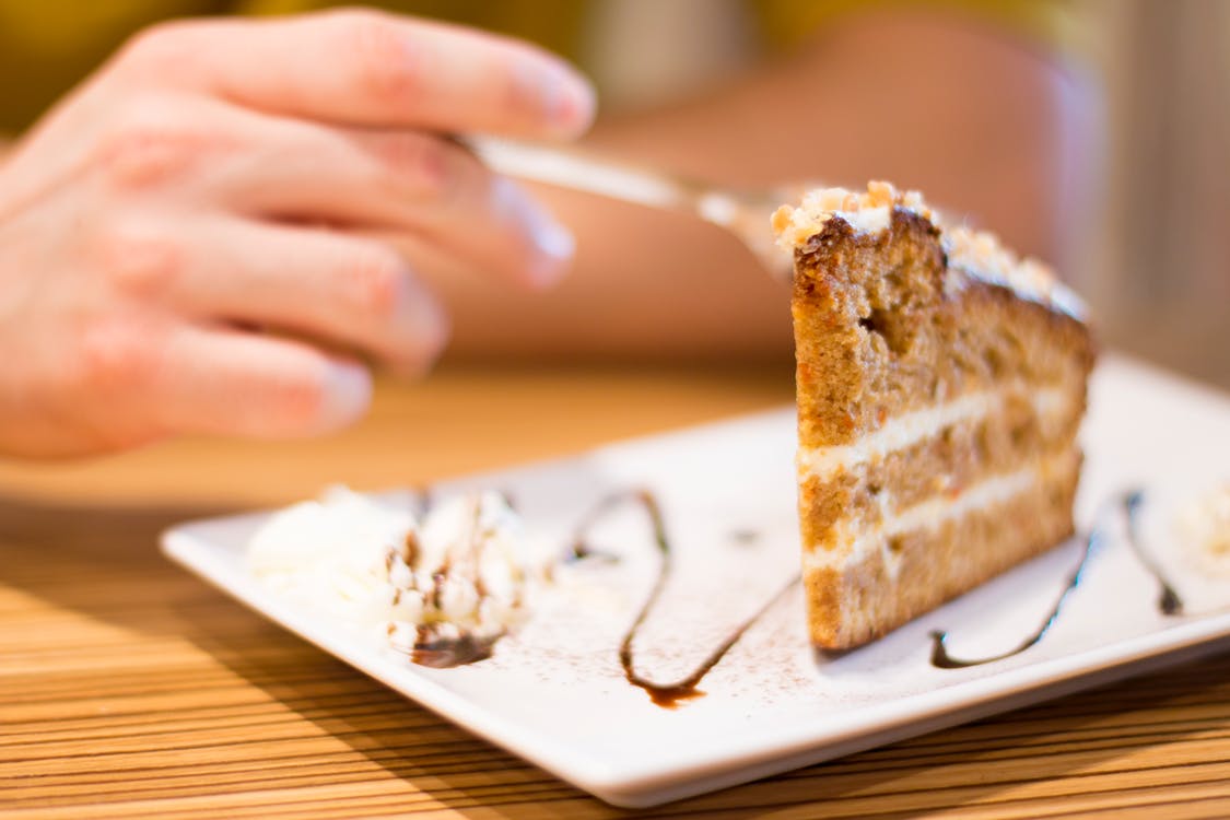 A rich person enjoying a slice of cake while people die of hunger