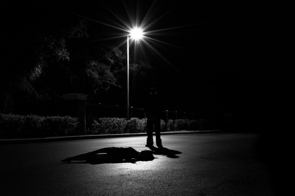 A man standing in the dark by a lamppost