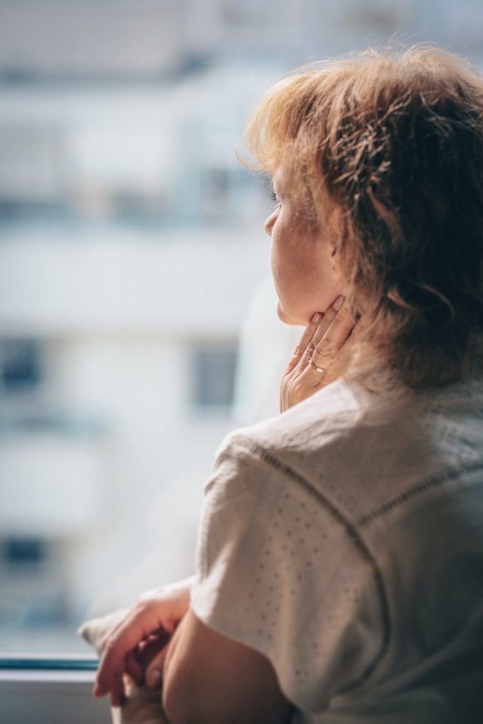 a woman feeling anxious and uneasy as she gazes outside the window