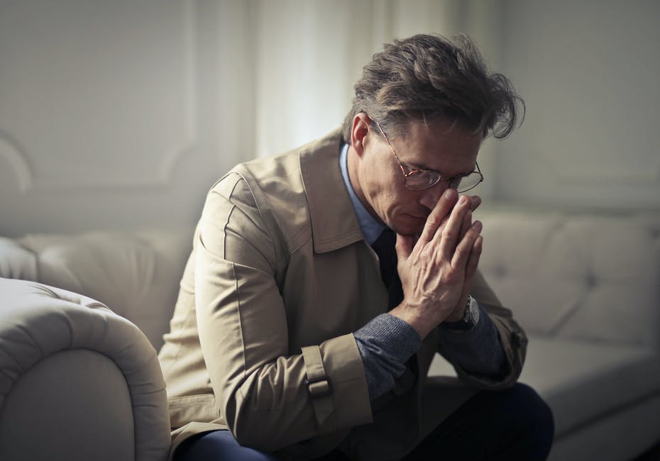 A man looks down, seeming worried and stressed out with his hands against his face