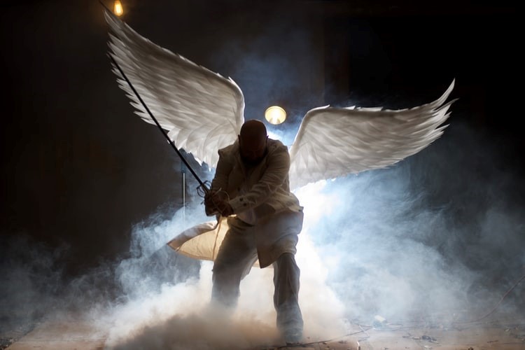 An angel-like warrior wielding a sword emerges from the shadows in smoke
