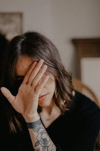 A woman hides her face in shame and self-doubt over her decisions.