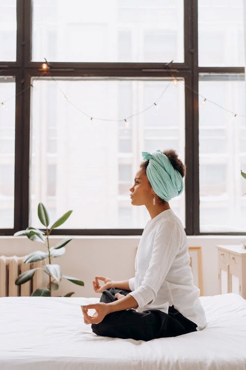 A woman sits on her bed meditating and channeling subconsciously