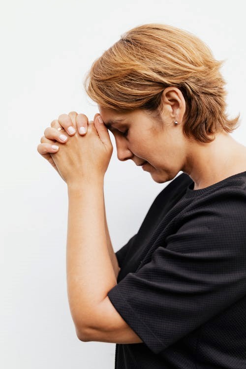 A woman closes her eyes and holds up her hands with hope and belief