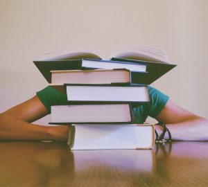 Student behind a pile of books